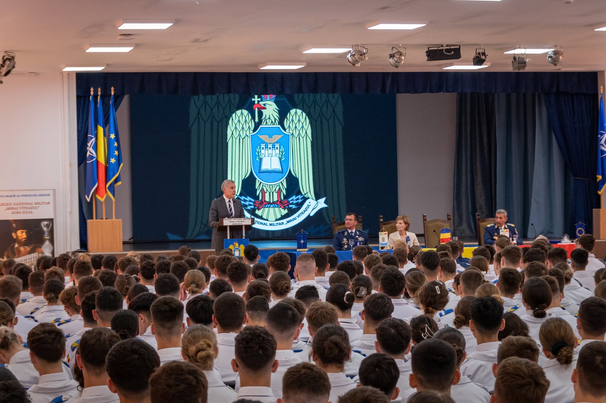 Ecran LED pe scena sălii de festivități a Colegiului Național Militar „Mihai Viteazul” din Alba Iulia, în timpul unui eveniment.